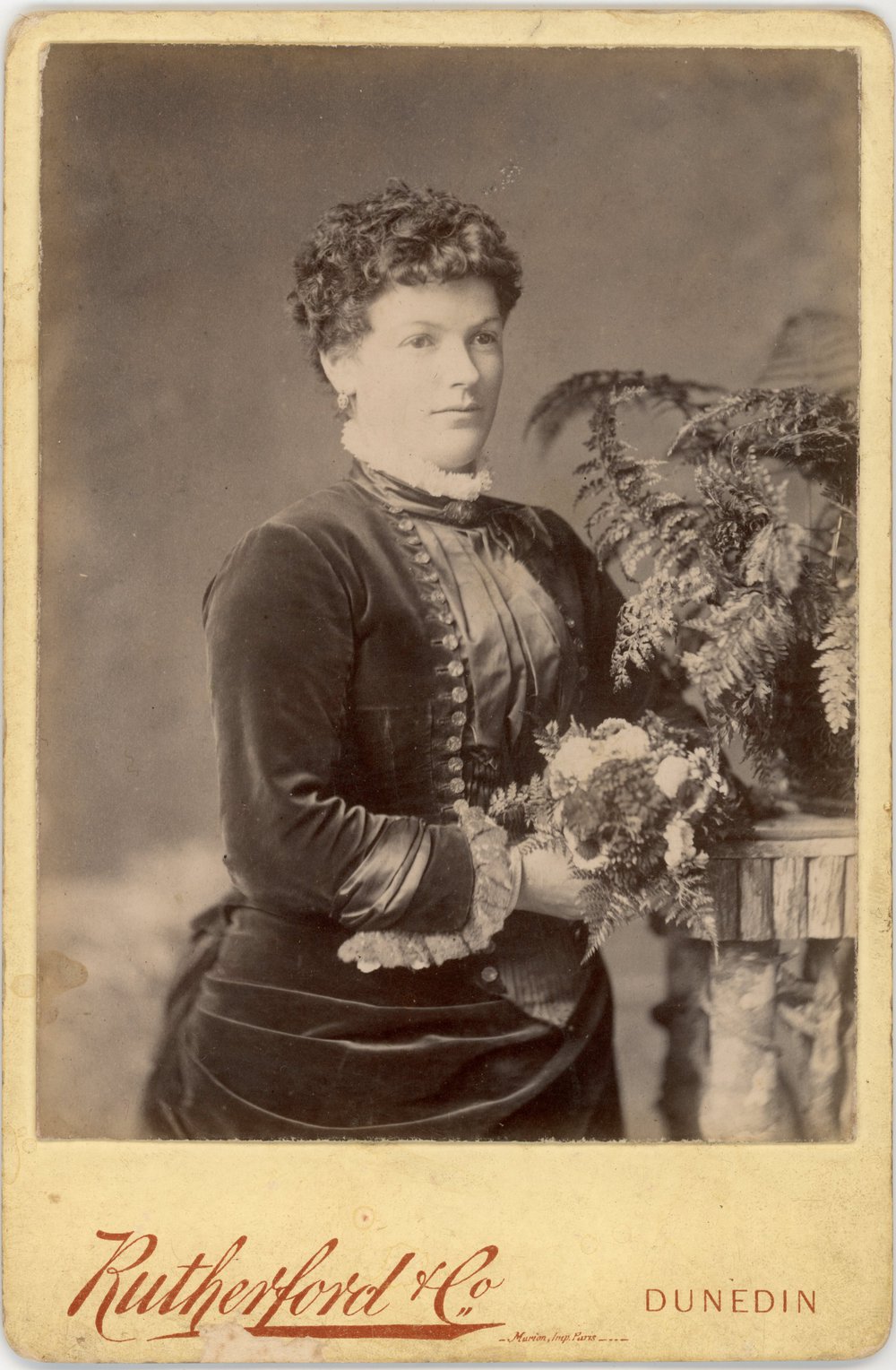 Studio portrait of a young lady dressed in dark dress with lace cuffs.