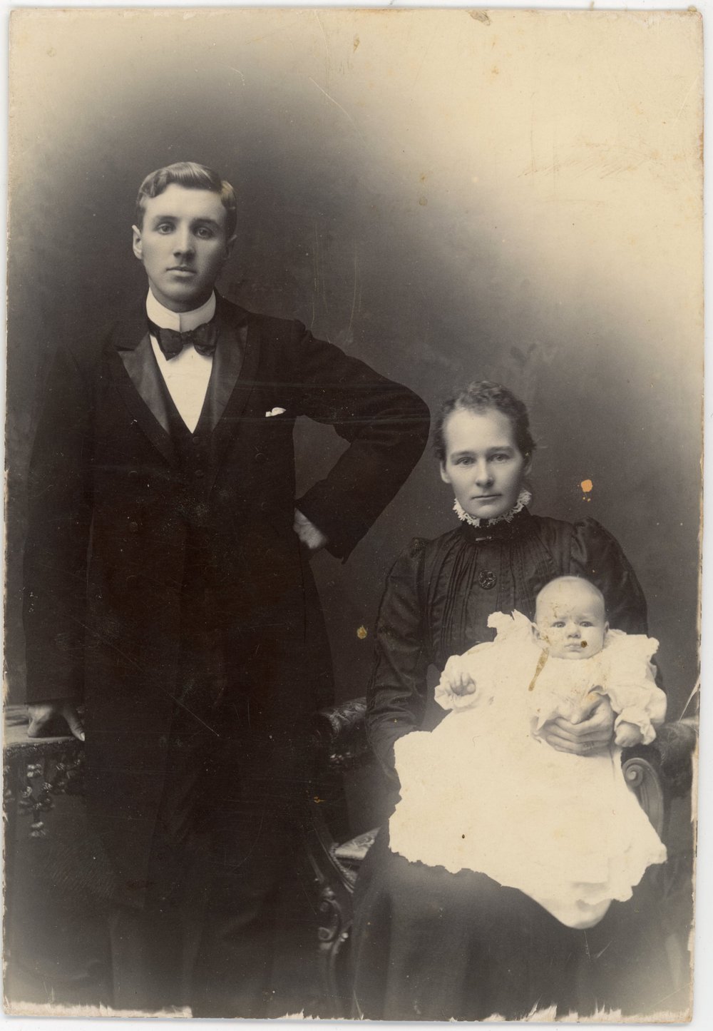 Formal studio portrait of a young couple and baby.